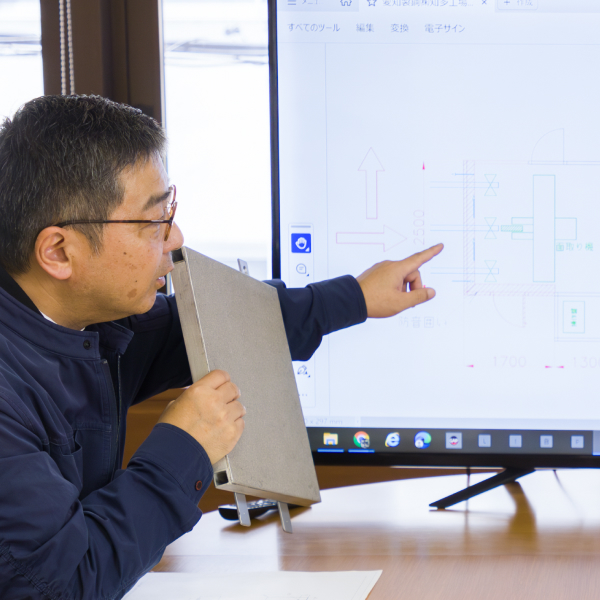 男性社員が図面を見ながら提案している様子。